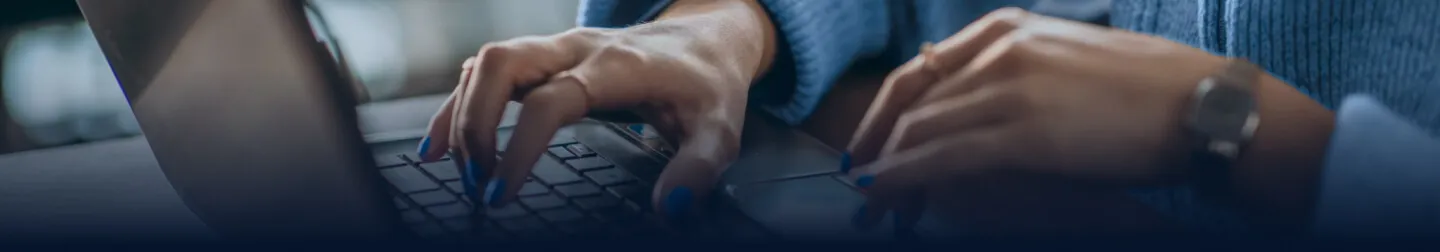 Foco de mãos femininas utilizando um laptop.