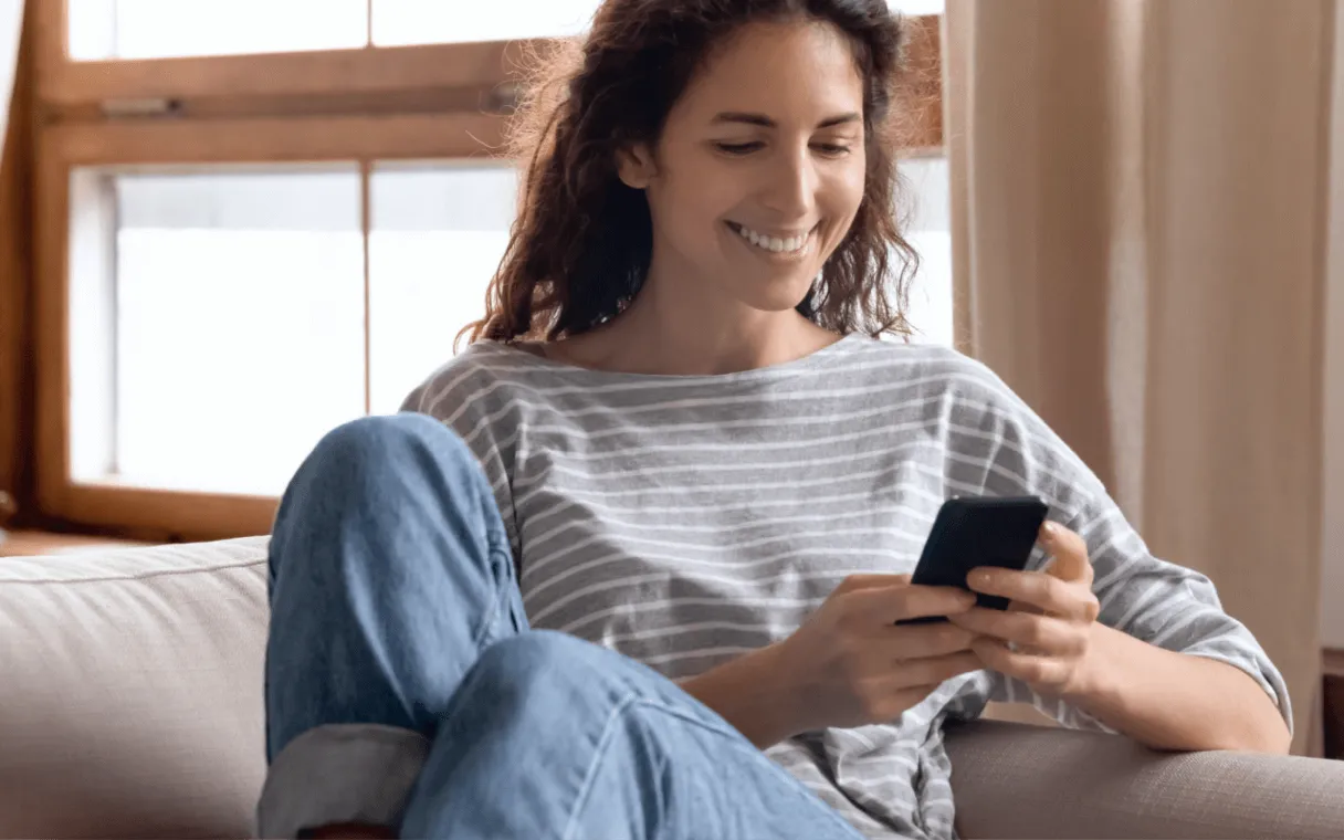 Imagem de uma pessoa utilizando um smartphone para realizar operações de câmbio com comodidade, simbolizando a praticidade dos serviços do BTG Pactual Empresas.