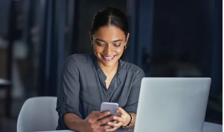 Executiva utilizando smartphone e laptop para operações financeiras