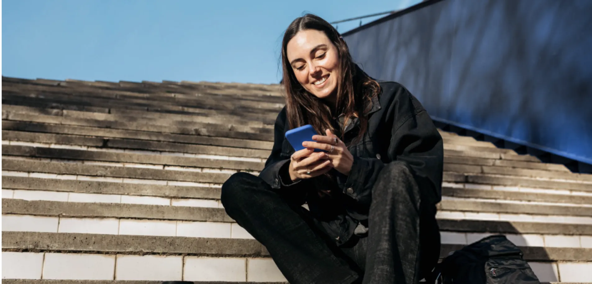 Empresária usando smartphone ao ar livre, representando a facilidade e conveniência do Open Finance no BTG Pactual Empresas.