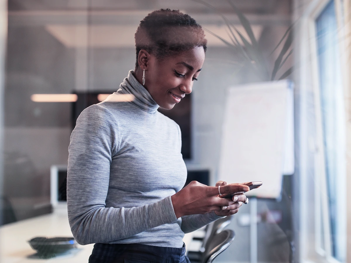 Mulher em pé segurando o celular fazendo um pix parcelado