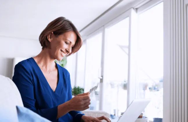 Mulher sorridente utilizando um laptop para solicitar contato sobre seguros empresariais, destacando a importância de proteger o patrimônio da empresa.