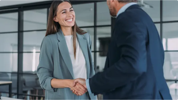 Homem e mulher sorrindo e apertando as mãos