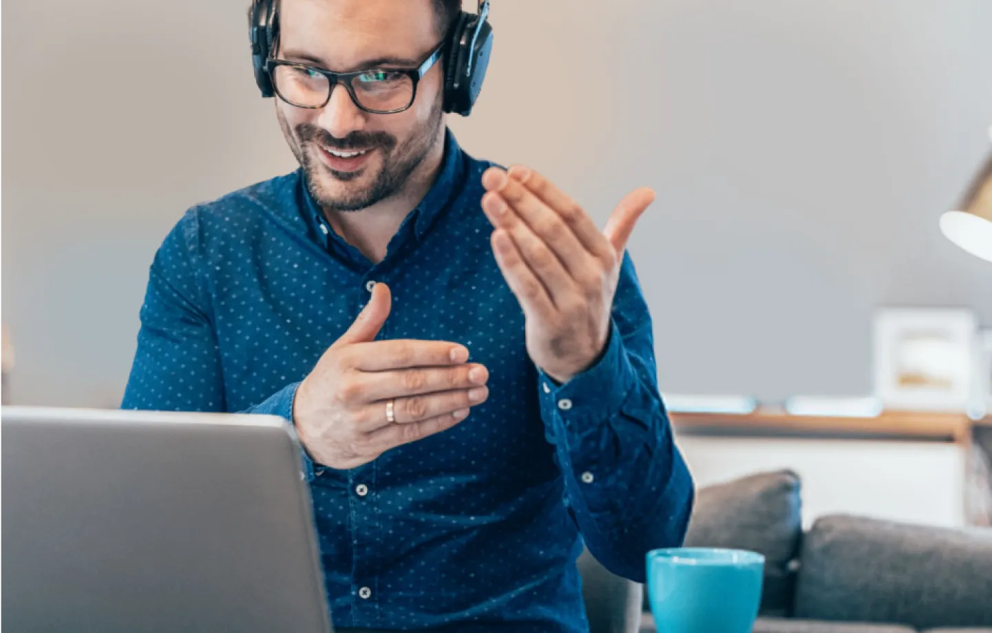 Homem de óculos em videoconferência em seu notebook, falando sobre as vantagens do BTG Empresas para o seu negócio.